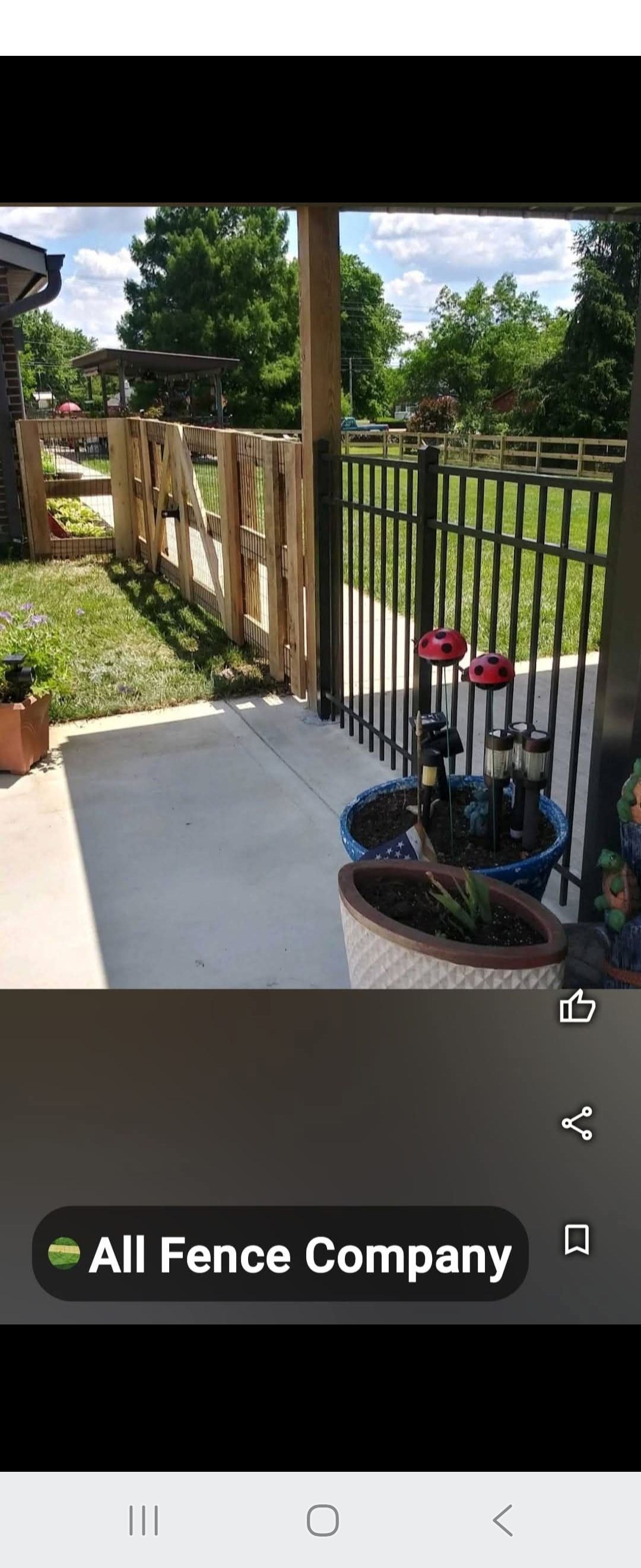 A wooden and metal fence in a yard with plants. 