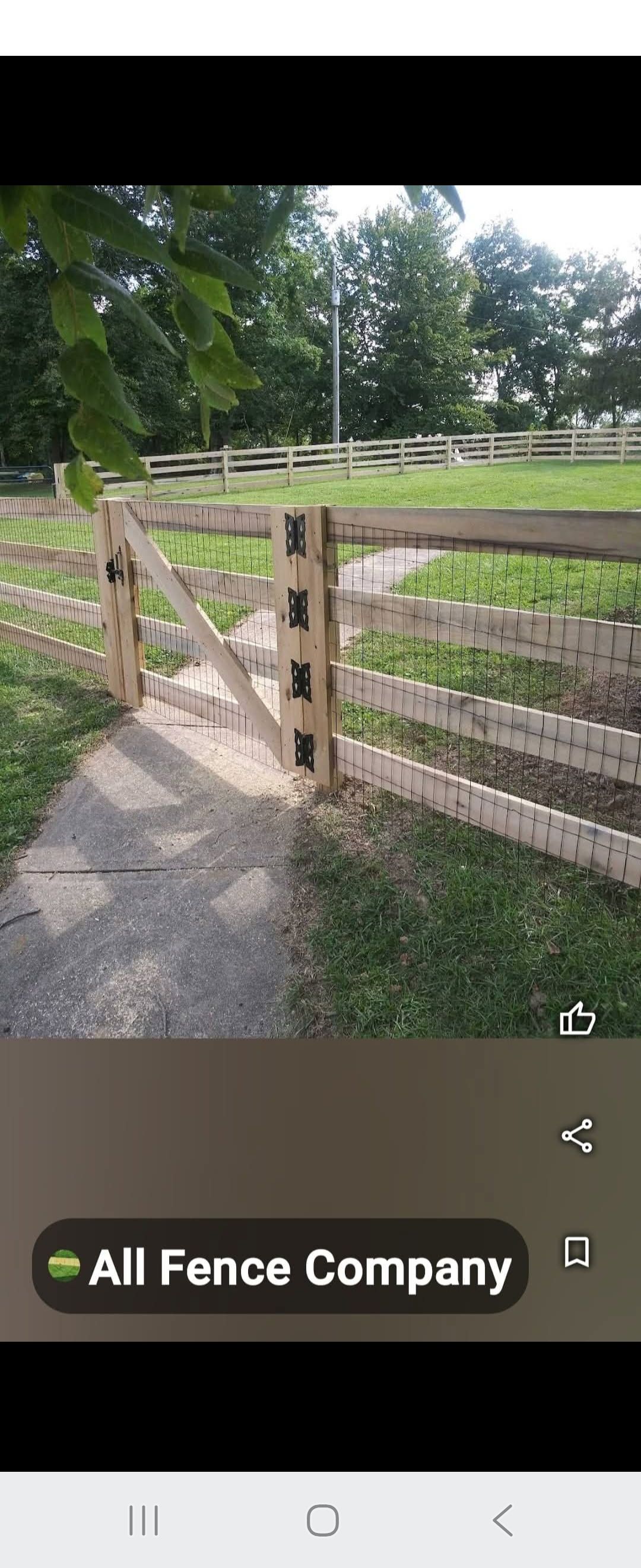Wooden fence with a gate, pathway, and grassy area with trees in the background.