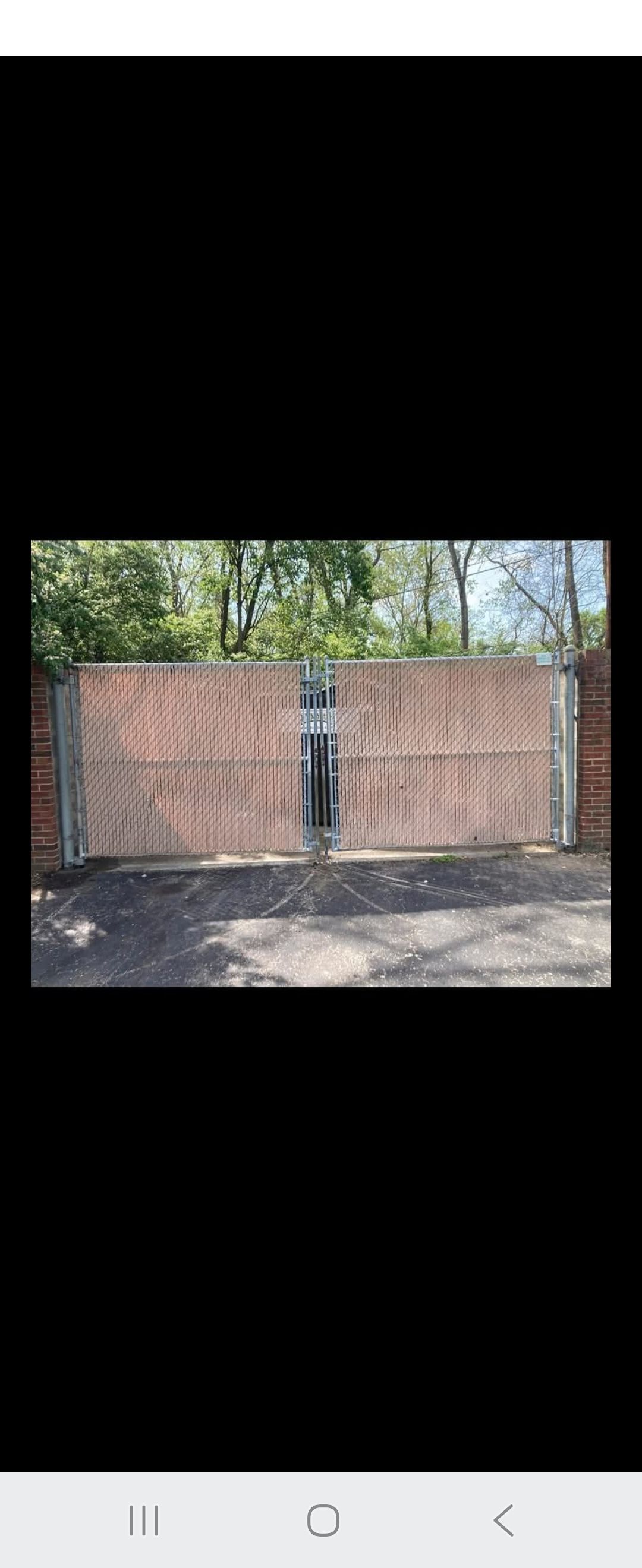 Wooden double gates in a brick setting with trees in the background.