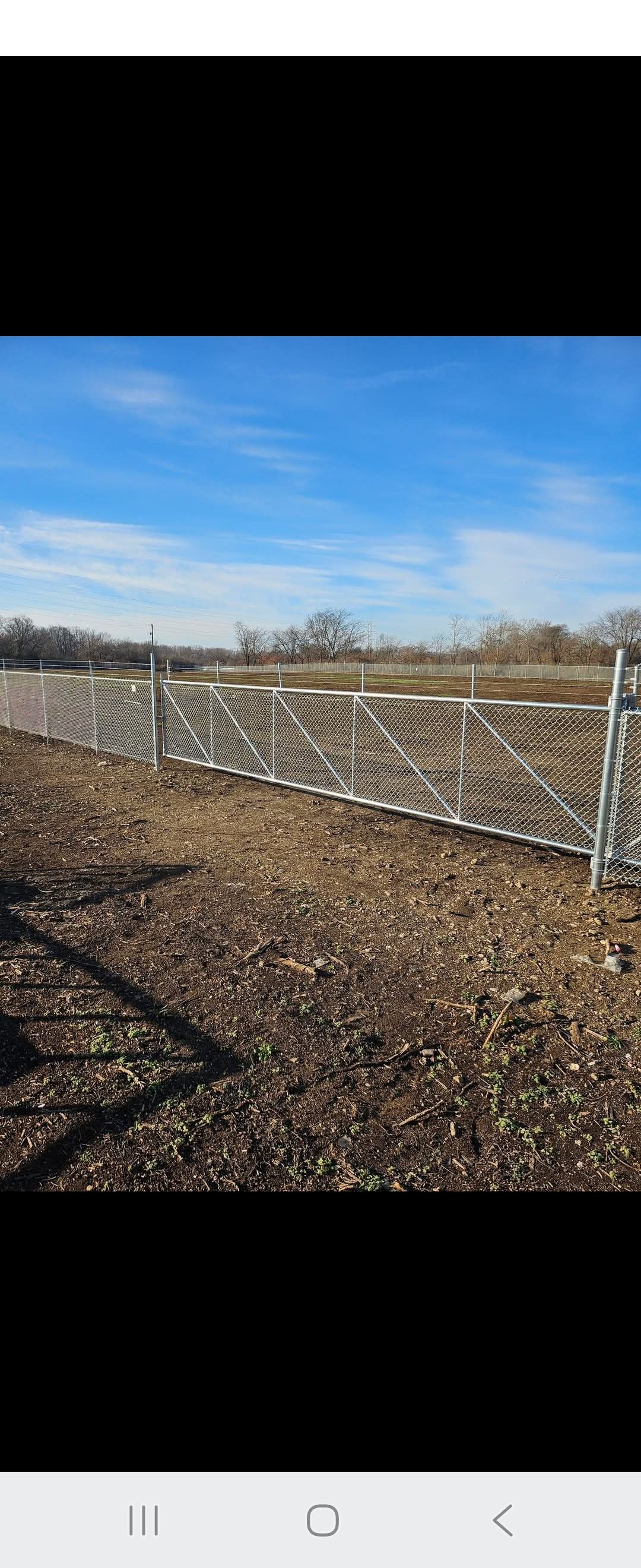 A weathered fence in a field under a bright blue sky.