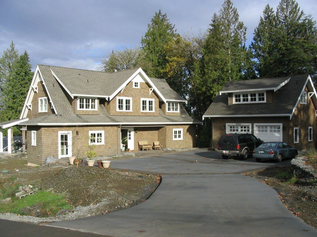 Two cars are parked in front of a large house