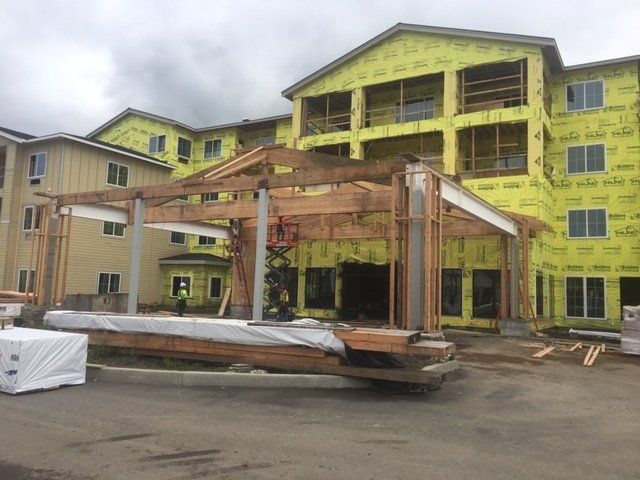 A large building under construction with a lot of wood in front of it.