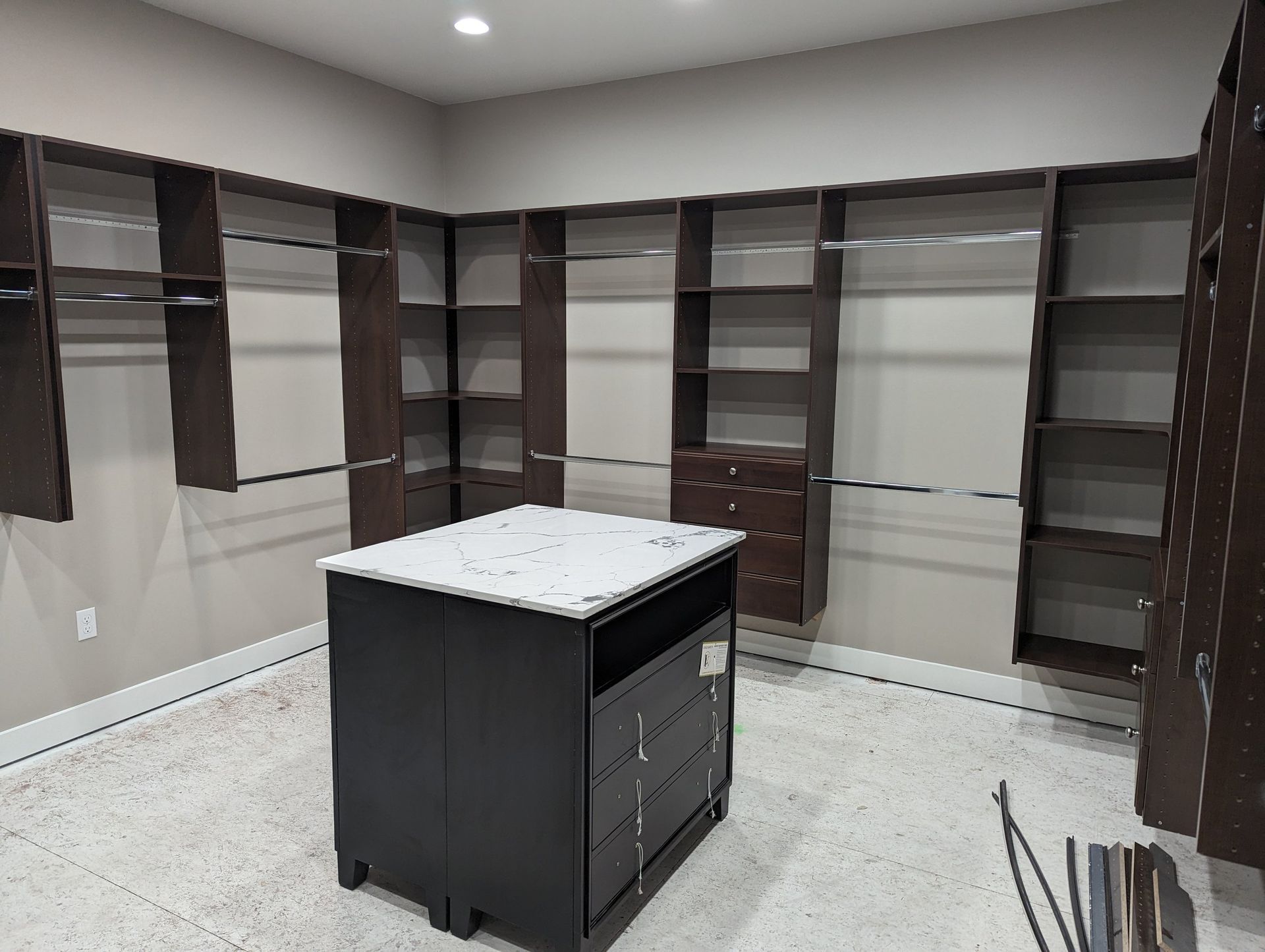 A walk in closet with lots of shelves and a large island in the middle.