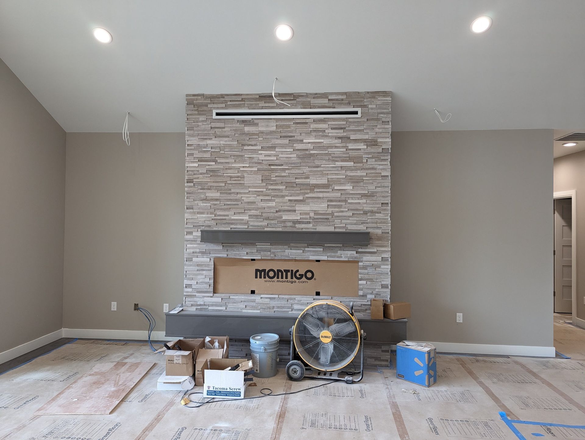 A living room under construction with a fireplace and a fan.