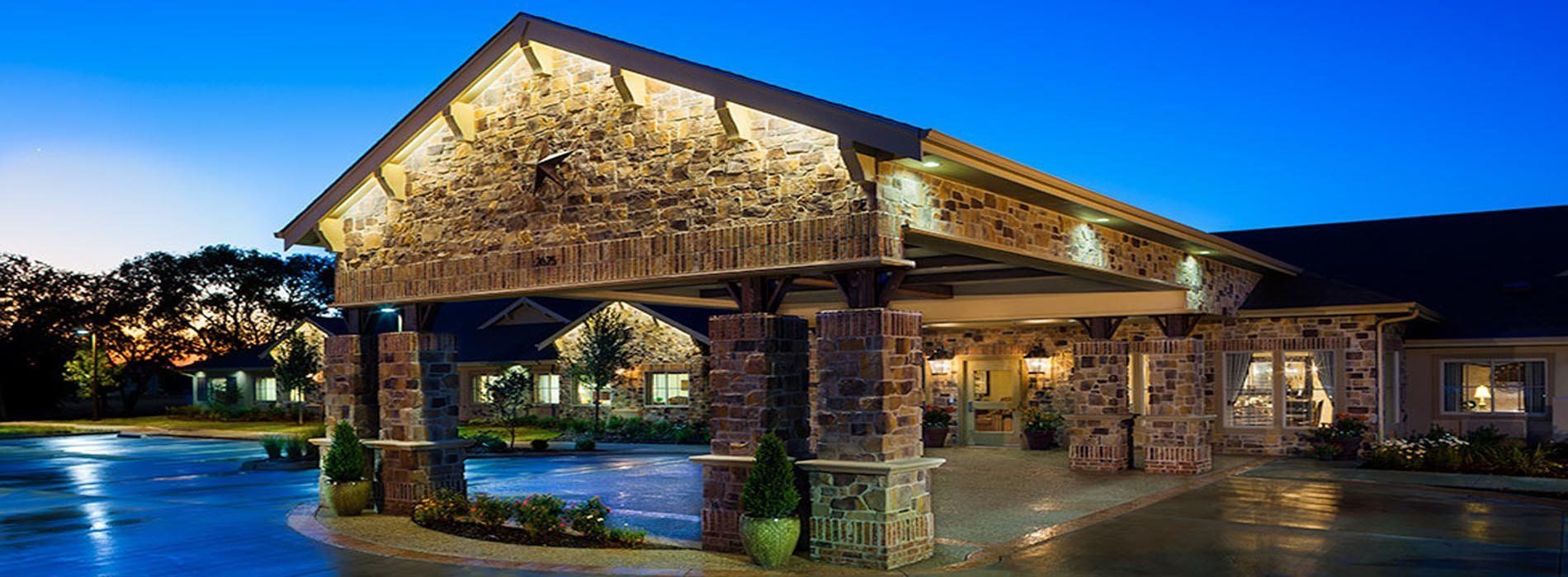 A large stone building with a pool in front of it at night.