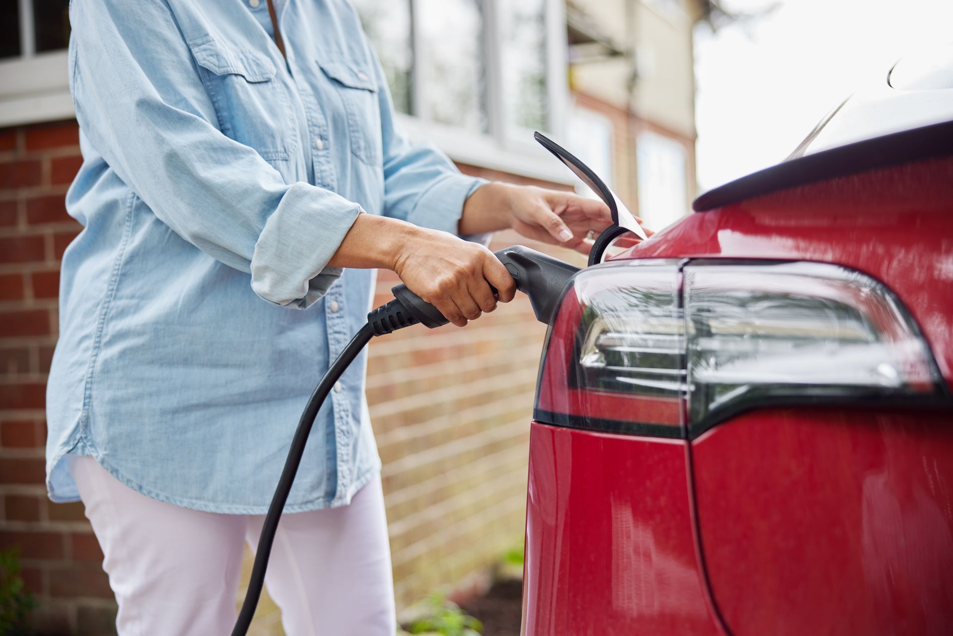 A woman using her home EV charger after an expert installation from a residential electrician.