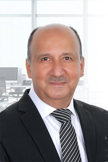 Man in suit and tie smiling, office background.