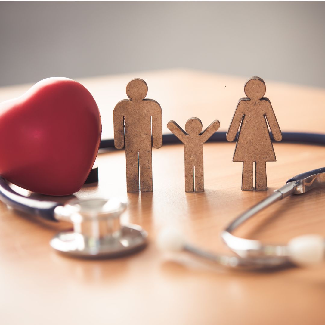 Red heart, family figures, and stethoscope on a wooden table.