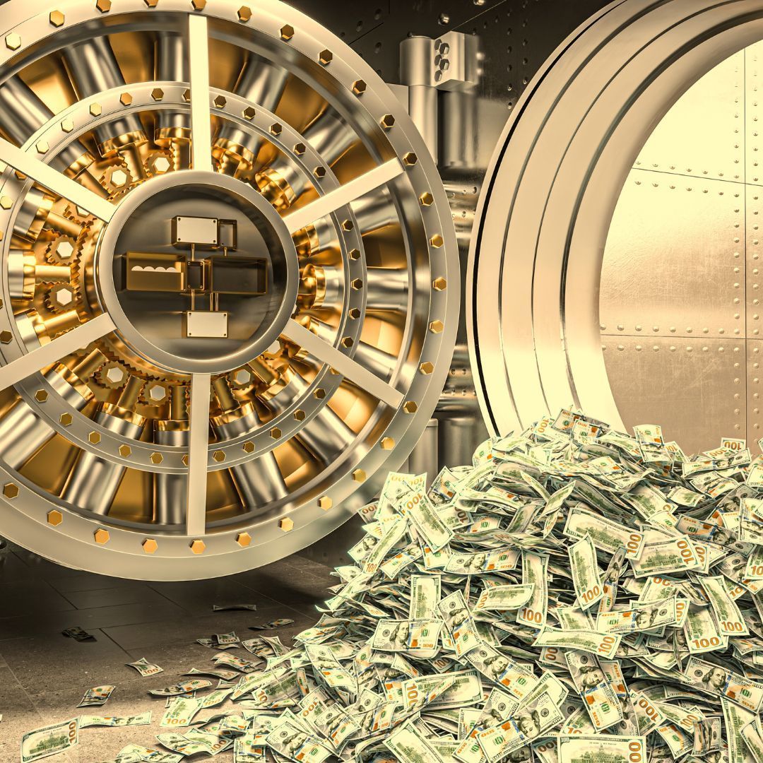Open bank vault with a large pile of cash spilling out.