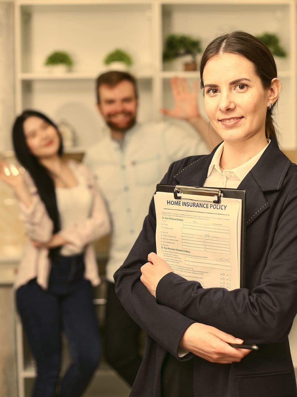 Real estate agent holding clipboard, smiling, with happy couple blurred in background.