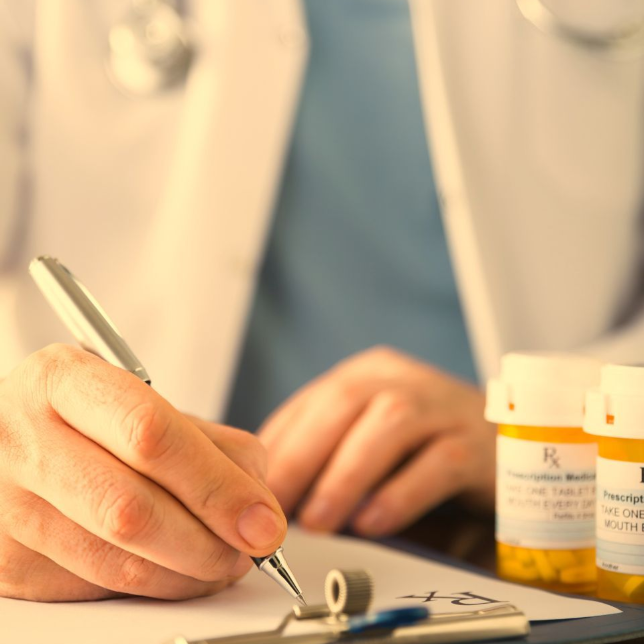 Doctor writing prescription with pill bottles in foreground.