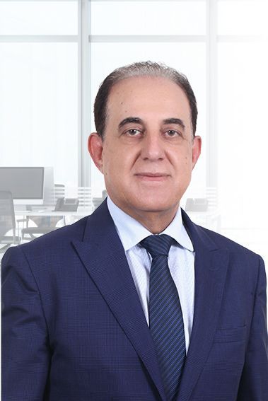 Man in blue suit, smiling slightly, in office setting.