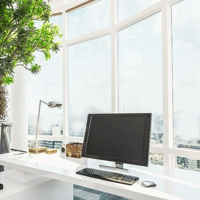 Desk with computer, keyboard, and mouse near a large window overlooking a cityscape.