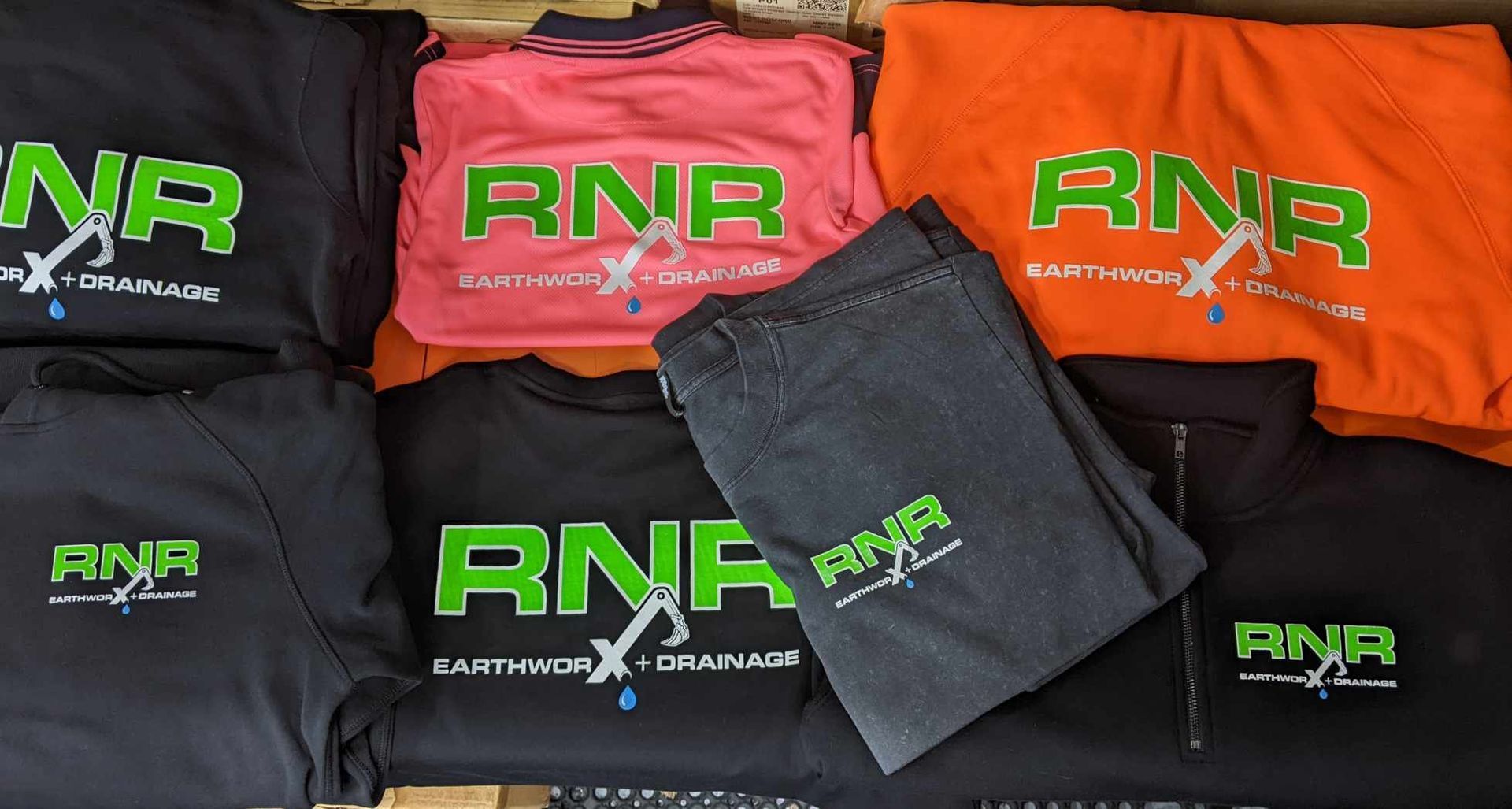 A Bunch of Mob Pod Shirts and Hats on A Table — CKM Screen Printing in West Gosford, NSW