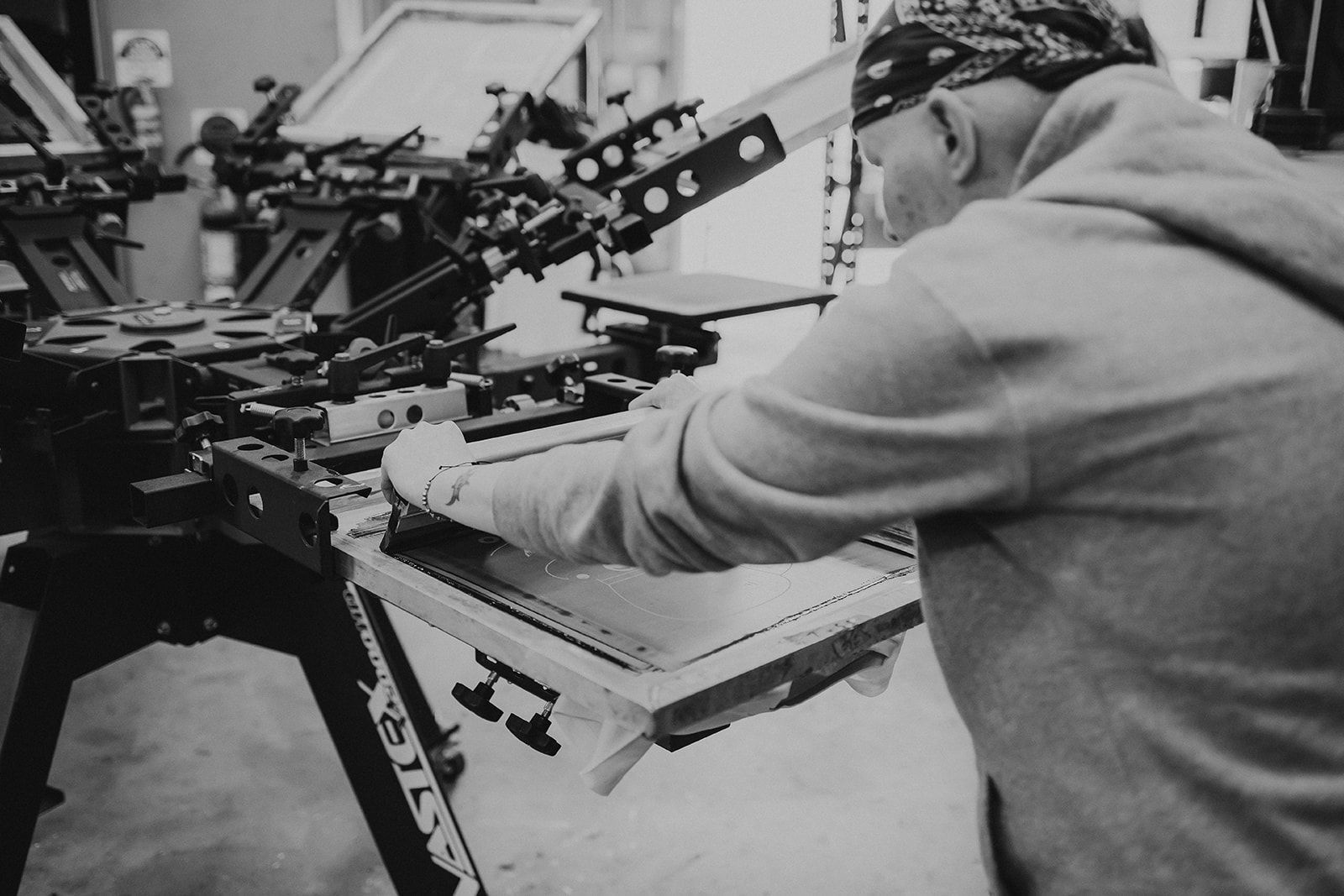 A T-Shirt Is Being Printed on A Screen Printing Machine in A Garage — CKM Screen Printing in West Gosford, NSW