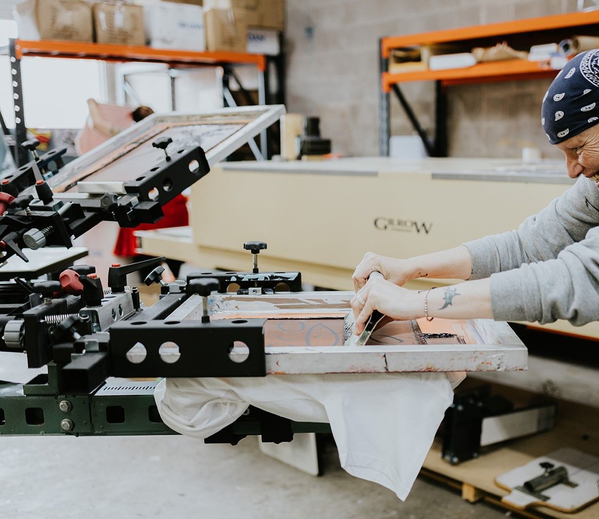 A Screen Printing Machine Is Sitting Next to A Bunch of Colorful Fabrics — CKM Screen Printing in West Tuggerah, NSW