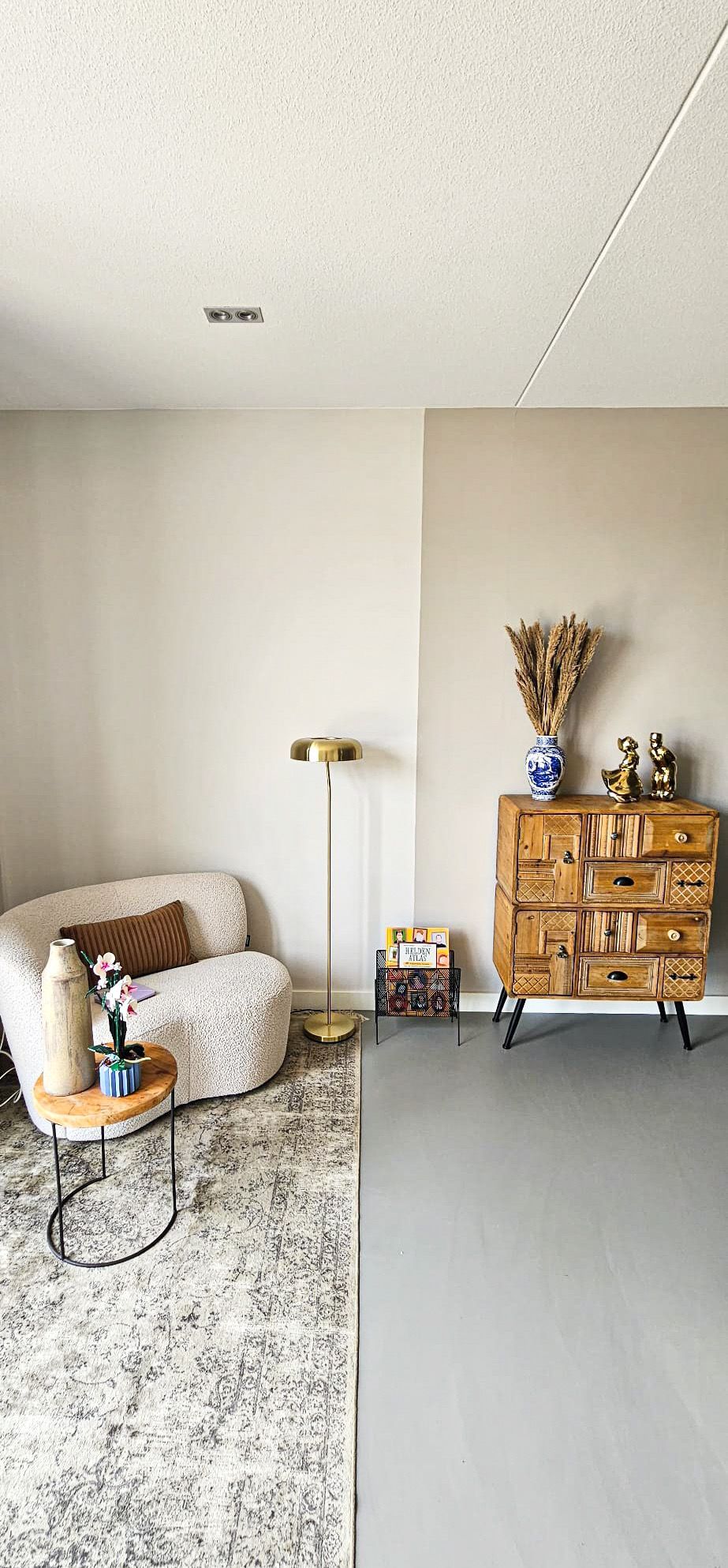 Een woonkamer met een bank, een ladekast en een vloerkleed.