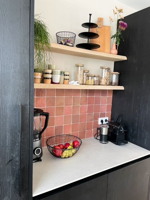 Zwarte keuken met nis. In het nisje een achterwand voorzien van roze zellige tegels. 