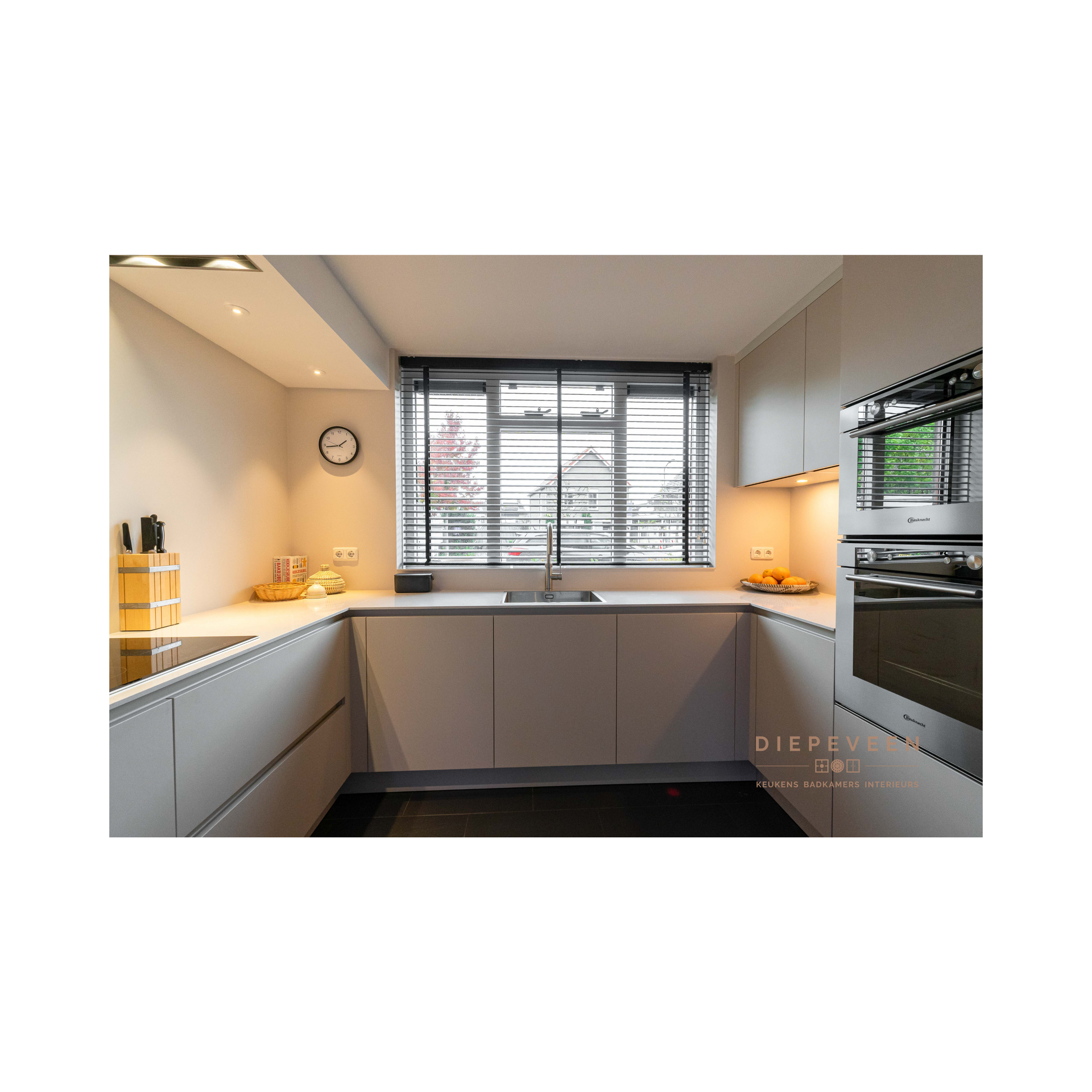 Een keuken met een spoelbak en een raam met jaloezieën