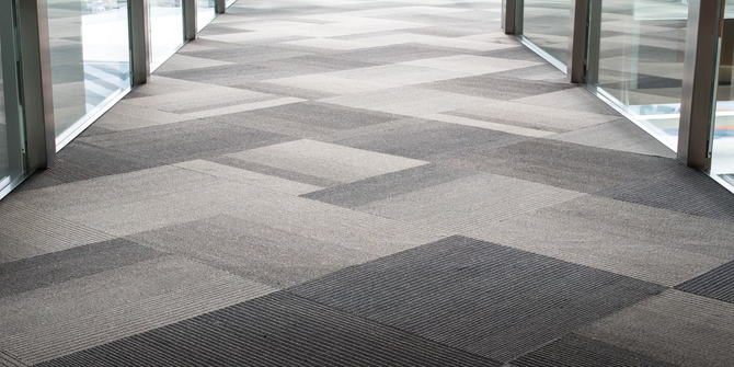 Hallway with geometric patterned carpet; glass windows and pillars on either side.