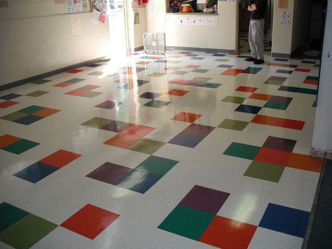 Colorful tiled floor in a room with a person standing near a doorway.