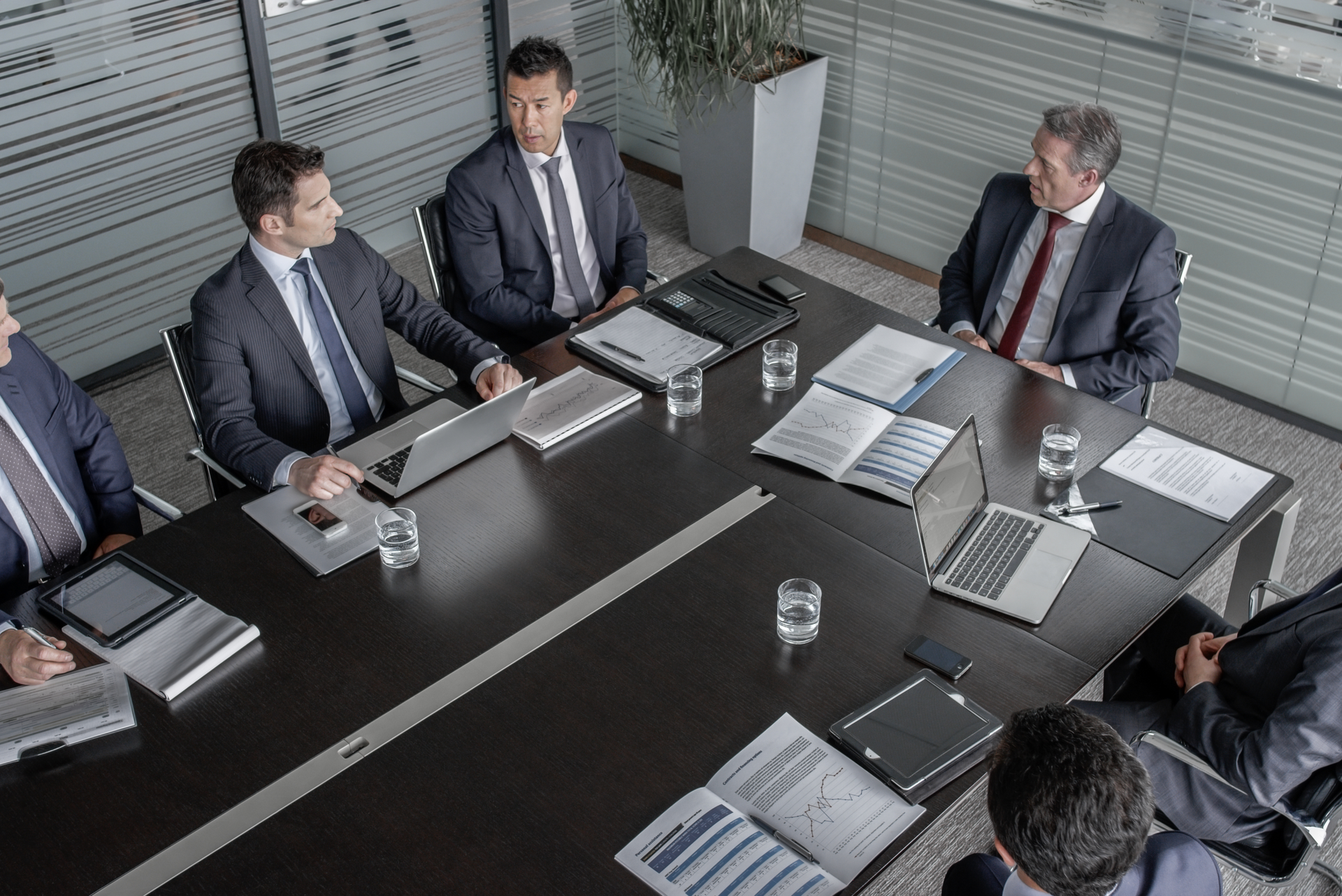 Exterior view of the New York Stock Exchange building with American flags. White columns and tall windows.
