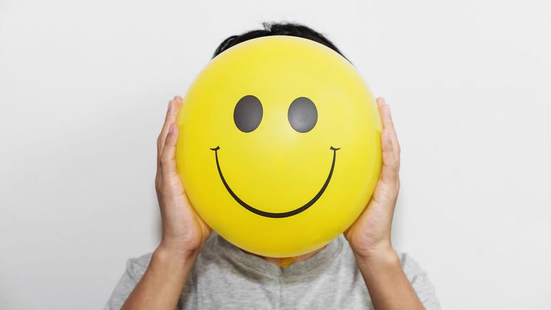 Mann hält sich Smiley vor Gesicht