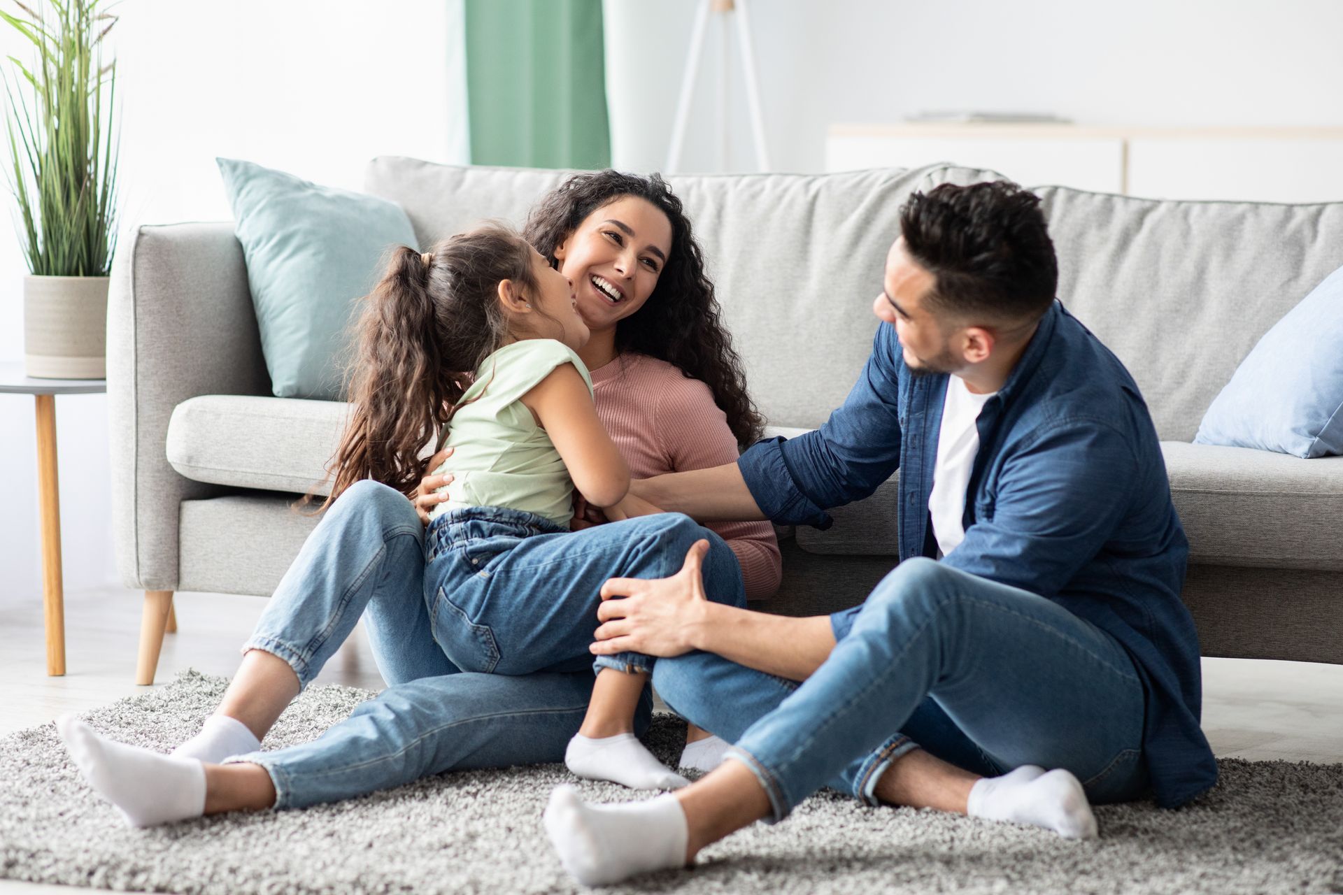 A family is sitting on the floor in front of a couch.