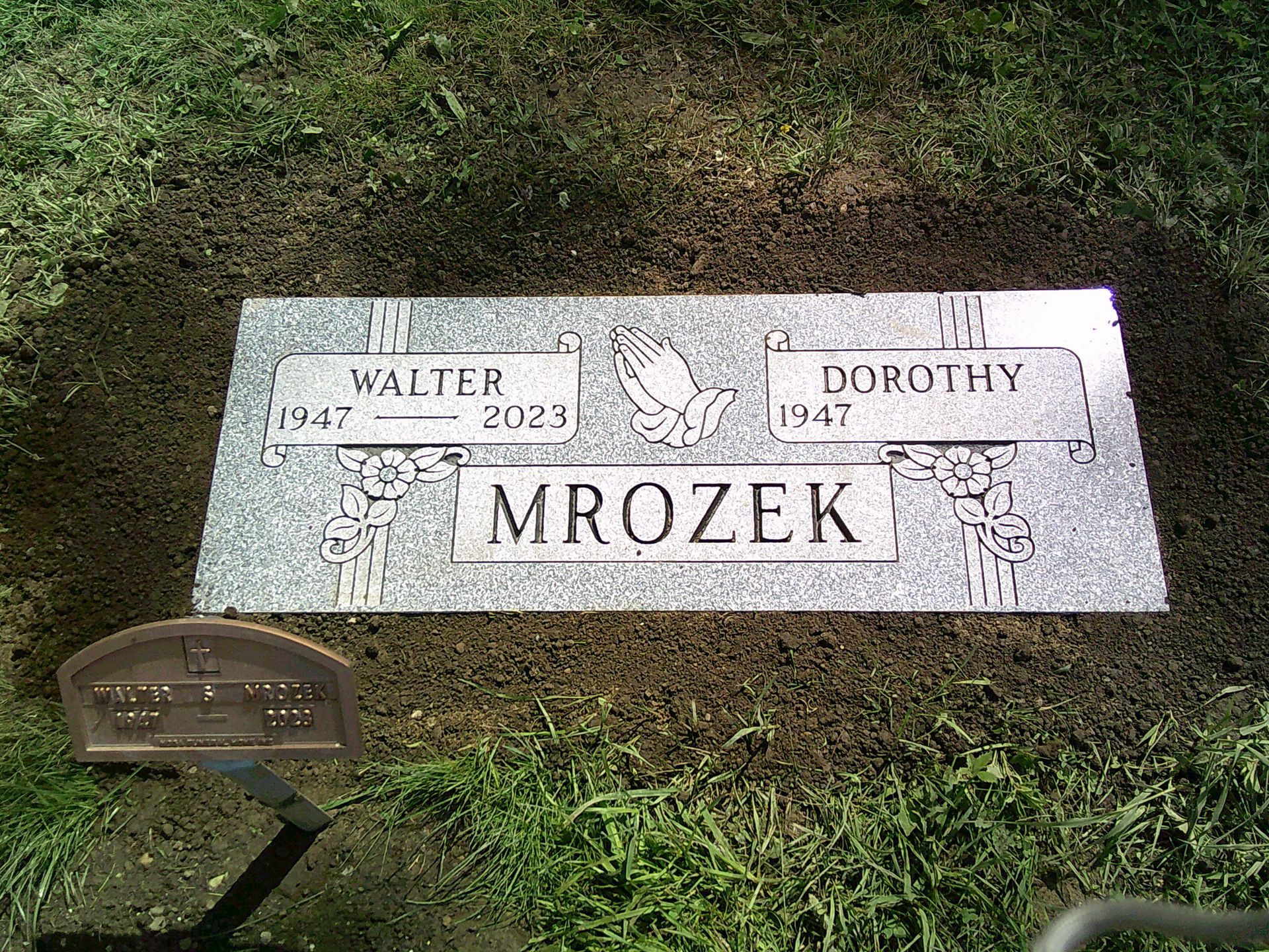 A gravestone for walter and dorothy mrozek is in the grass.