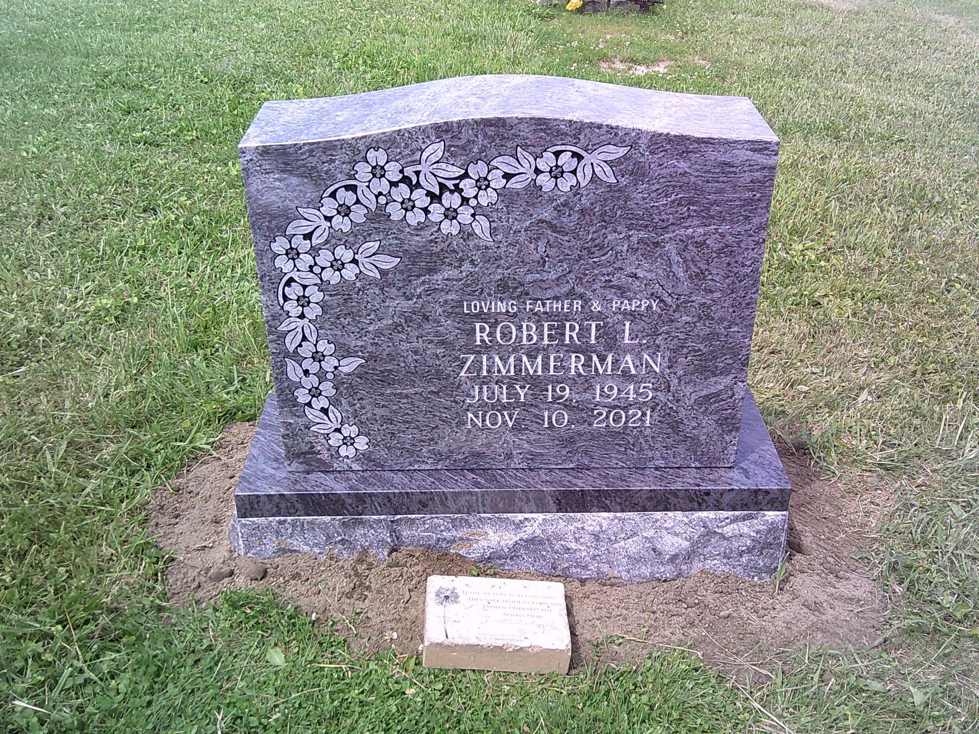 A gravestone in a cemetery with flowers on it.