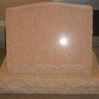 A gravestone is sitting on top of a concrete base on a table.