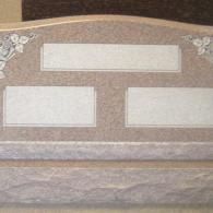 A gravestone with three plaques on it is sitting on a table.