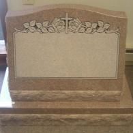 A gravestone with a cross and leaves on it is sitting on a table.