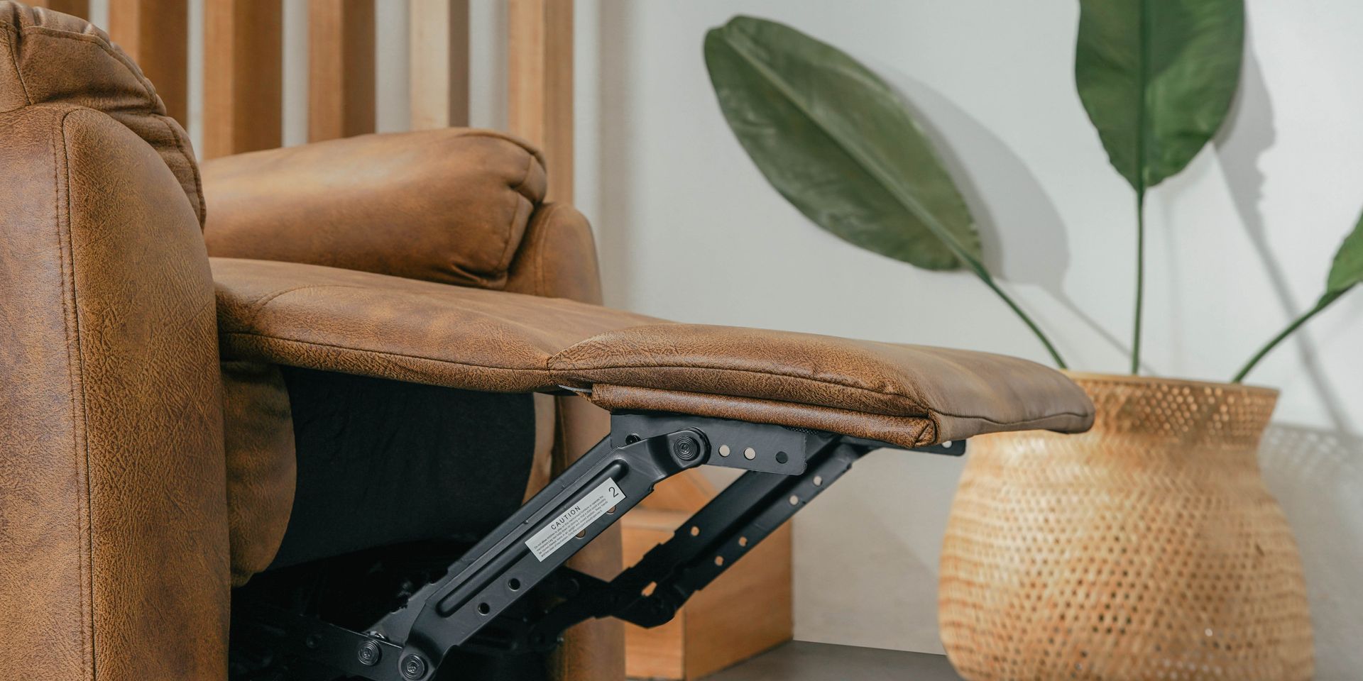 A recliner is sitting next to a potted plant in a living room.