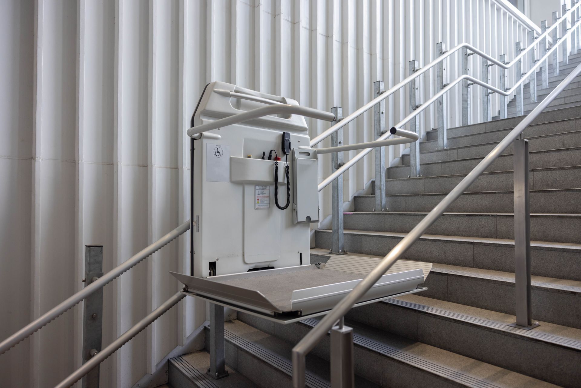 A stair lift is attached to the side of a set of stairs.