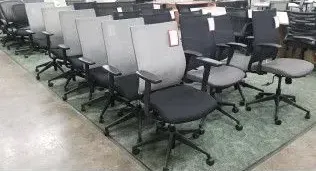 A row of office chairs sitting on top of a rug in a store.