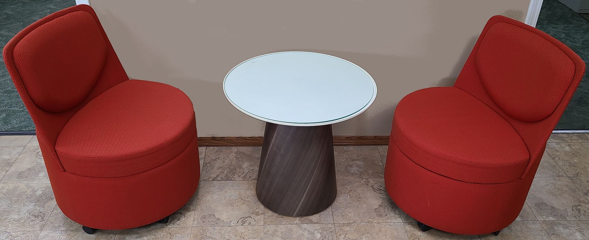 Two red chairs and a white table are sitting next to each other.