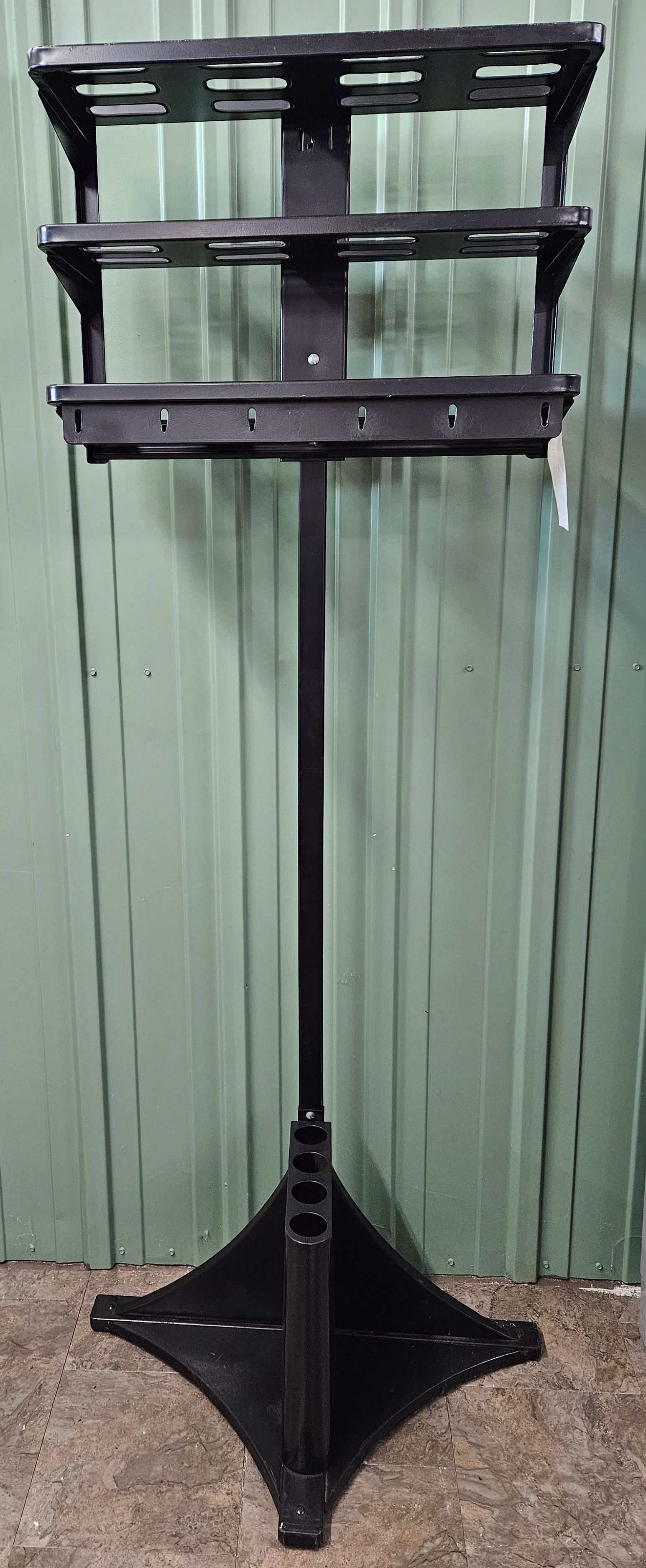 A black music stand is sitting in front of a green wall.