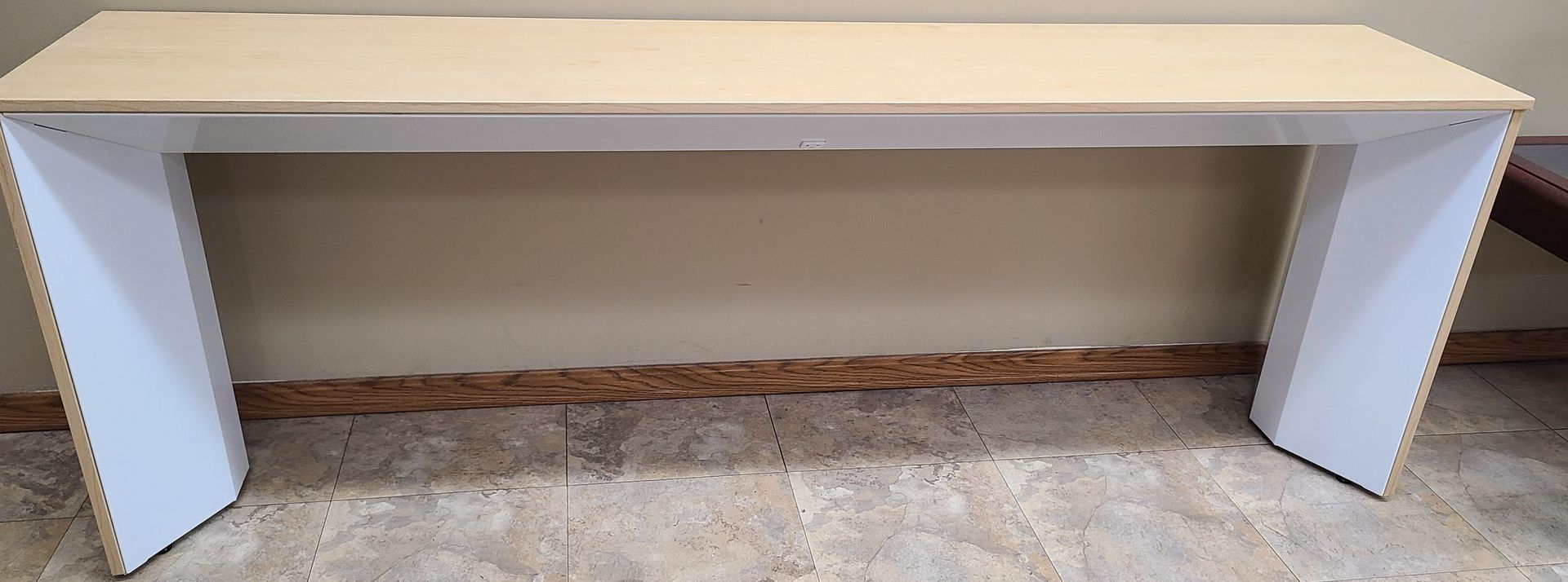 A wooden table with white legs is sitting on a carpet in a room.