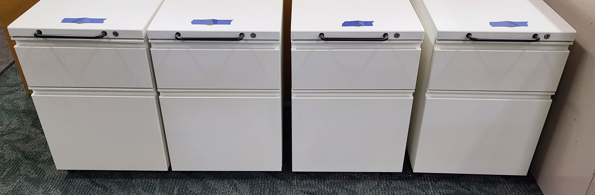 Three white filing cabinets are sitting next to each other on a carpeted floor.