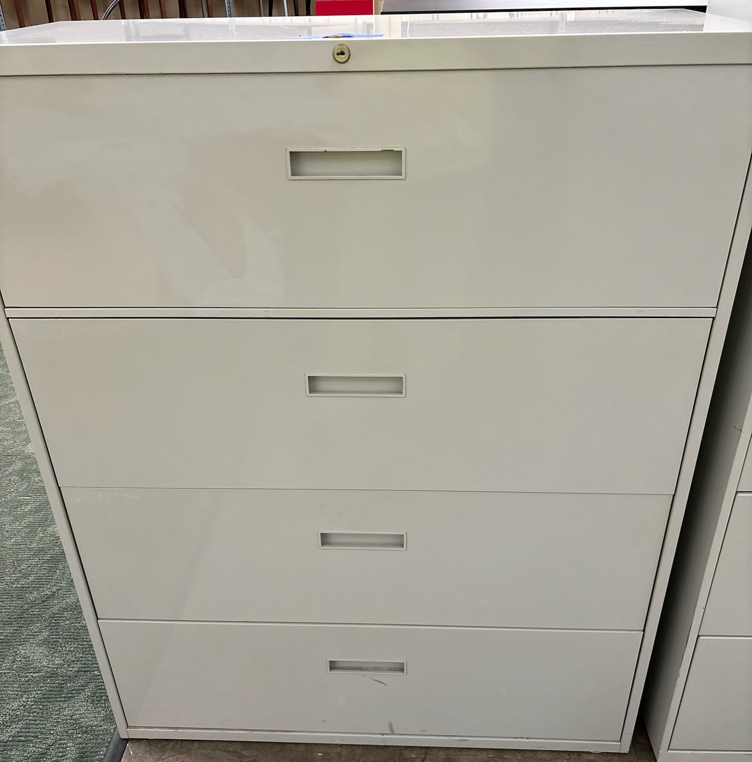 A white filing cabinet with three drawers is sitting on the floor.