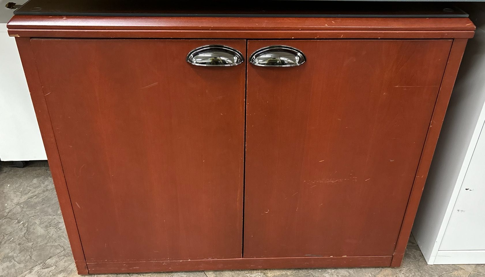 A small wooden cabinet with two doors and chrome handles.
