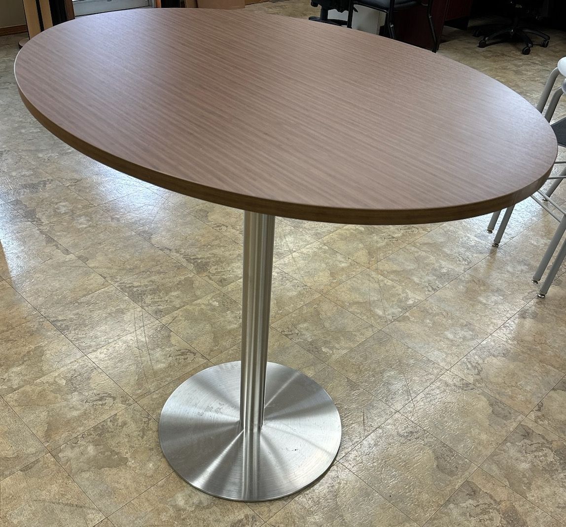 A wooden table with a stainless steel base is sitting on a tiled floor.