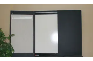 Two white boards are hanging on a wall next to a plant.