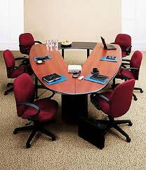 A conference room with a large oval table and chairs.