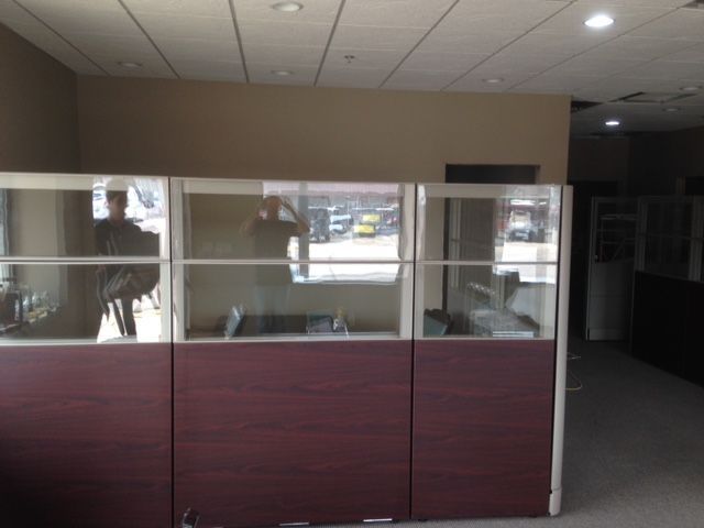 A cubicle with a reflection of a person in it