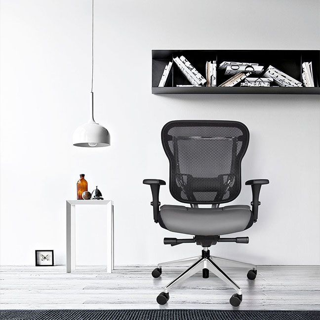 A black office chair is sitting in a room next to a shelf with books on it