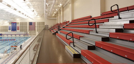 A row of bleachers in a stadium with a pool in the background.