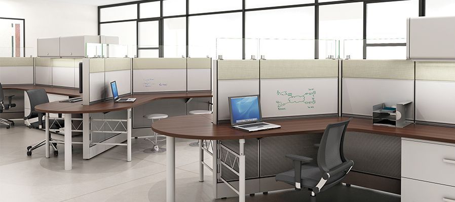 A row of cubicles in an office with a laptop on a desk.