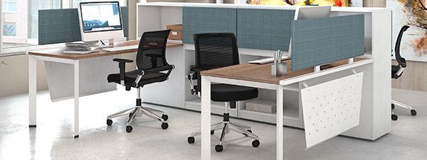 A cubicle with two desks and two chairs in an office.